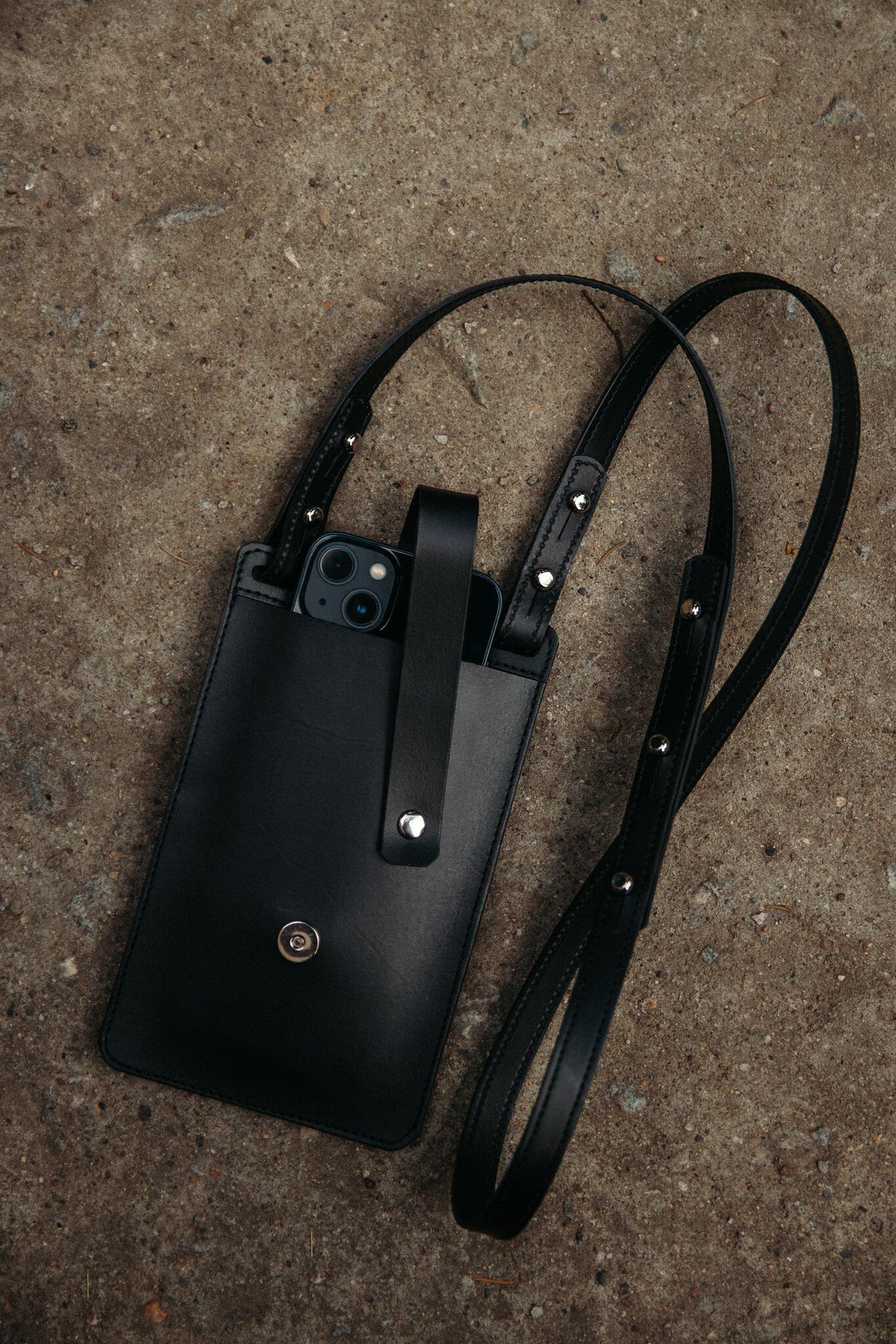 2. Black Stella Soomlais By Your Side phone bag with iPhone 13 Pro and detachable strap on concrete background