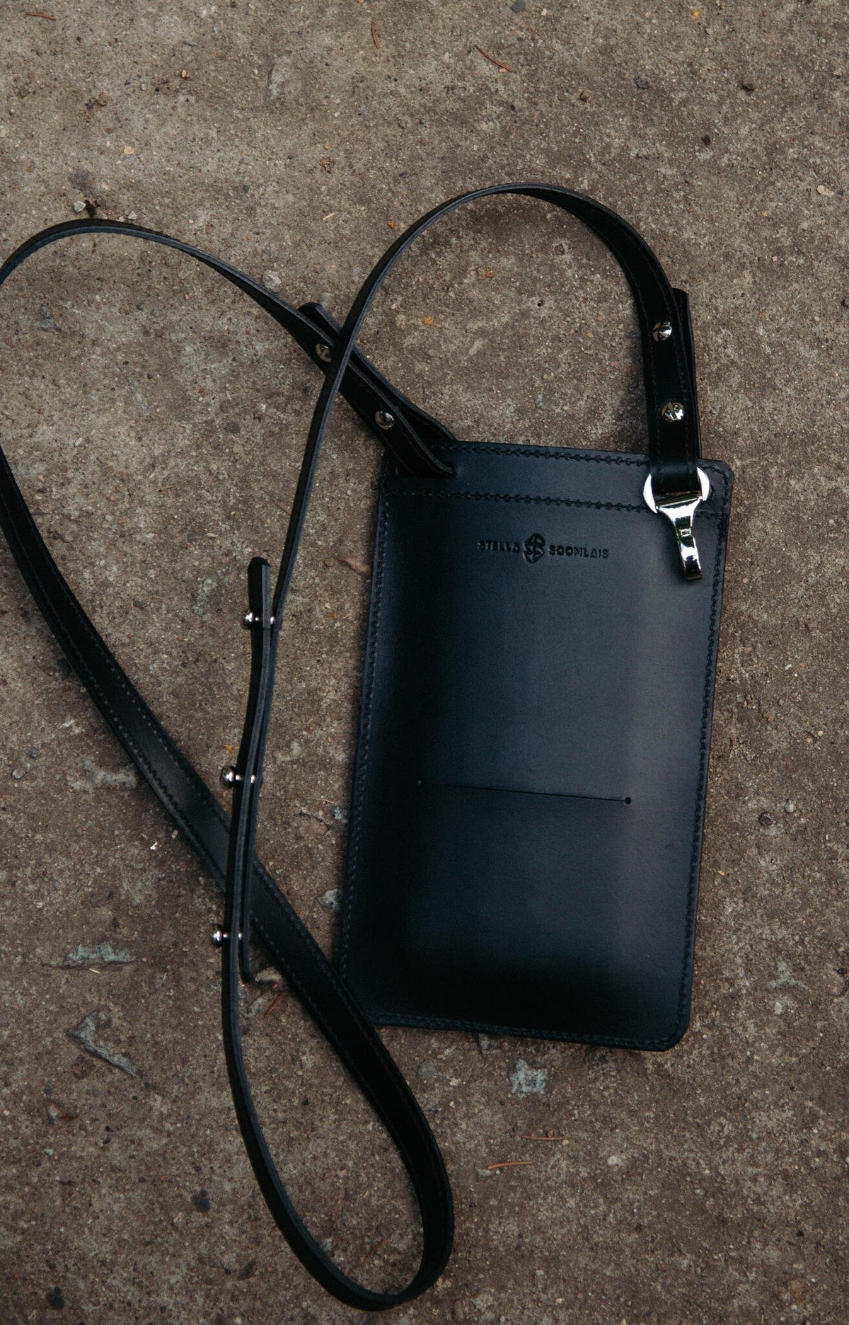 10. Black Stella Soomlais By Your Side phone bag with detachable strap and carabiner on concrete