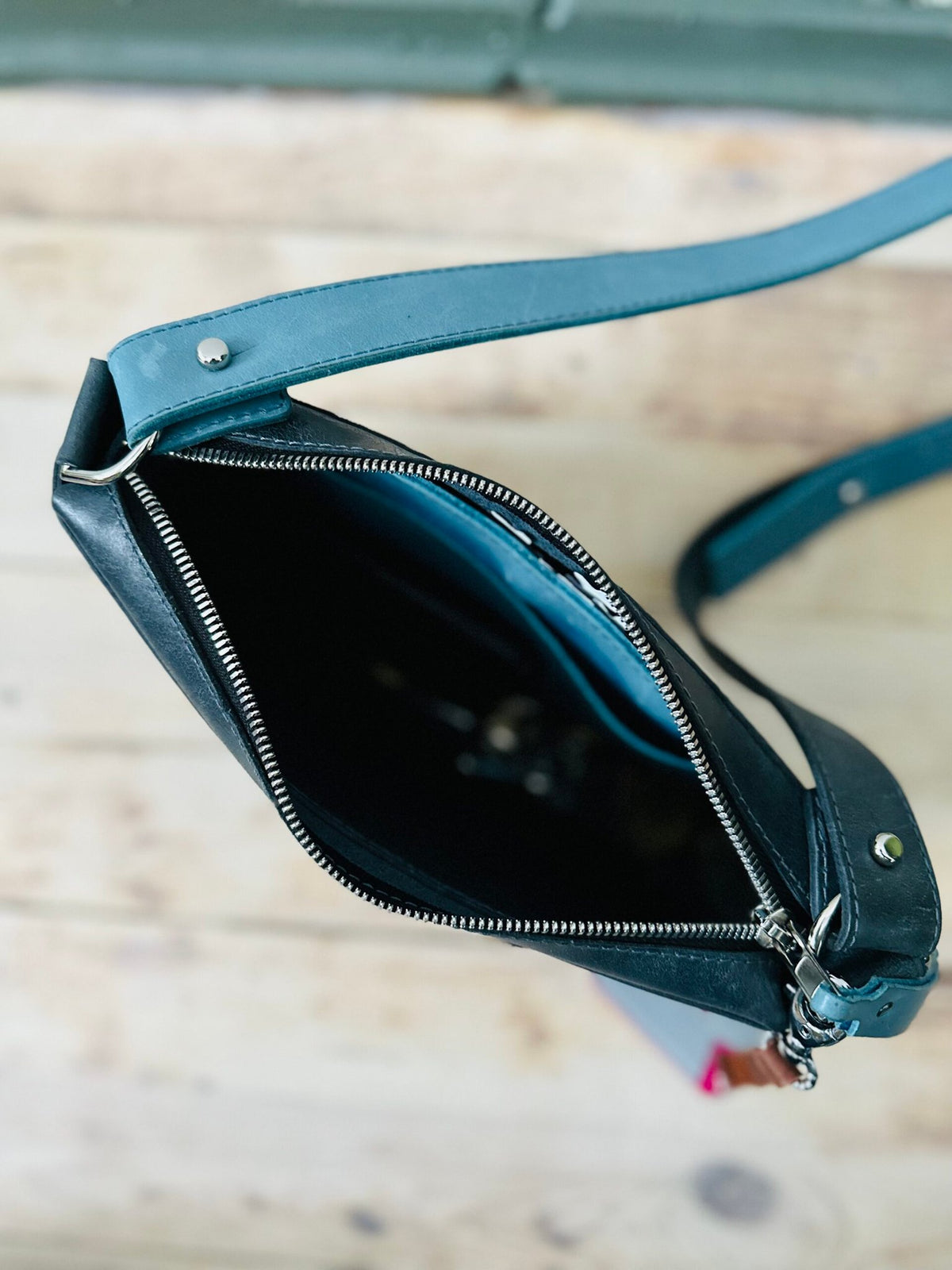 7. Top view of eleriinseim TOURIST crossbody leather bag in Atlantic blue, showing zippered closure and interior space