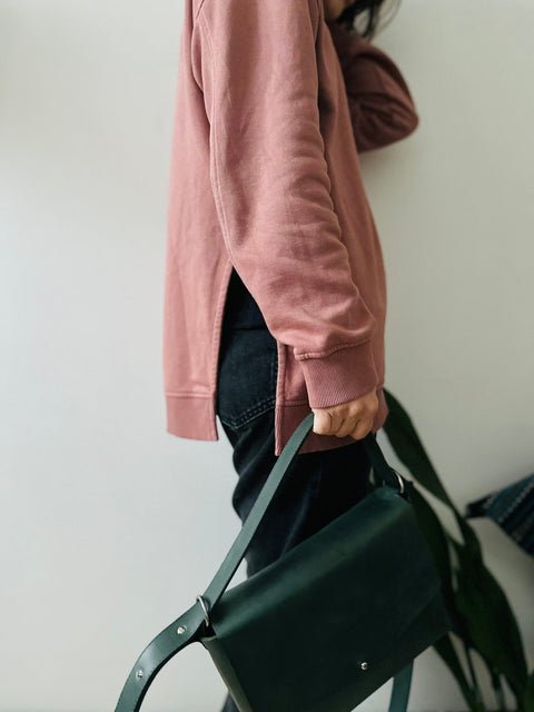 4. Woman holding eleriinseim TOURIST crossbody leather bag in Forest green, demonstrating casual wear style
