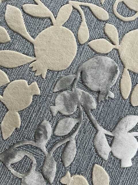 3. Close-up of pomegranate branch pattern in beige and grey on blue wool rug