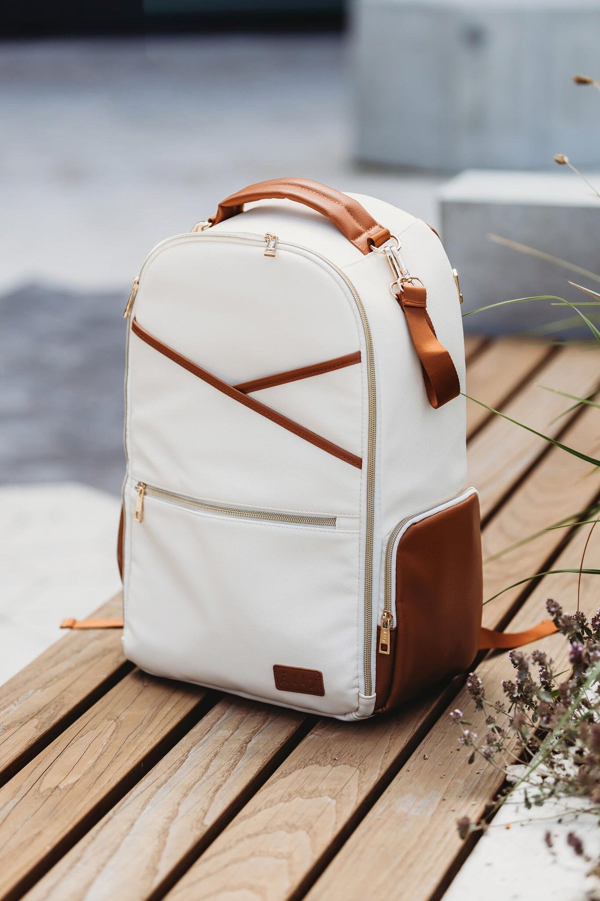 6. Lifestyle image of Ally Scandic Cappuccino Diaper Backpack on wooden bench