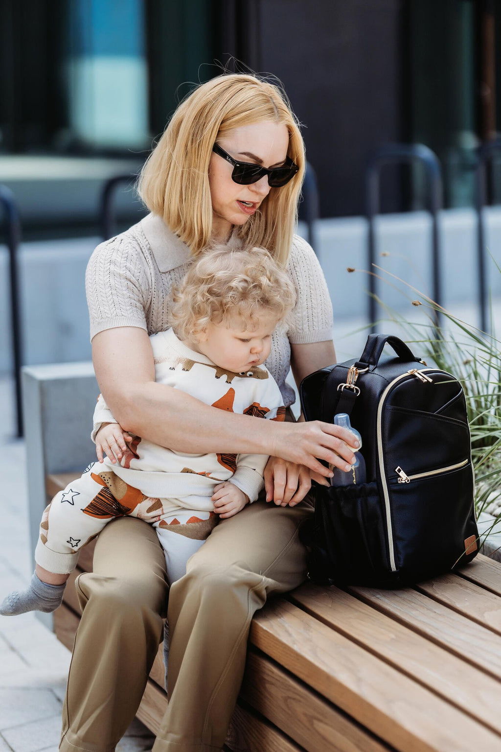 3. Woman sitting with child and Ally Scandic Small Espresso Diaper Backpack on bench