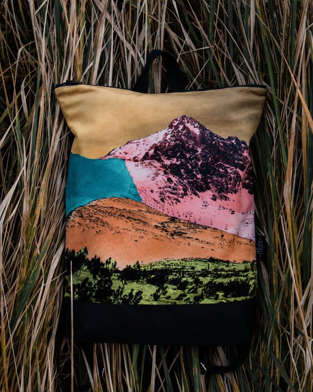 3. Muni Bold Mountains backpack with vibrant mountain design in natural setting