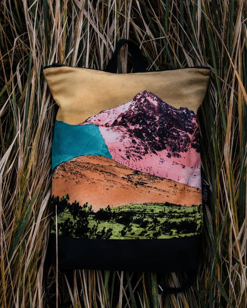 3. Muni Bold Mountains backpack with vibrant mountain design in natural setting