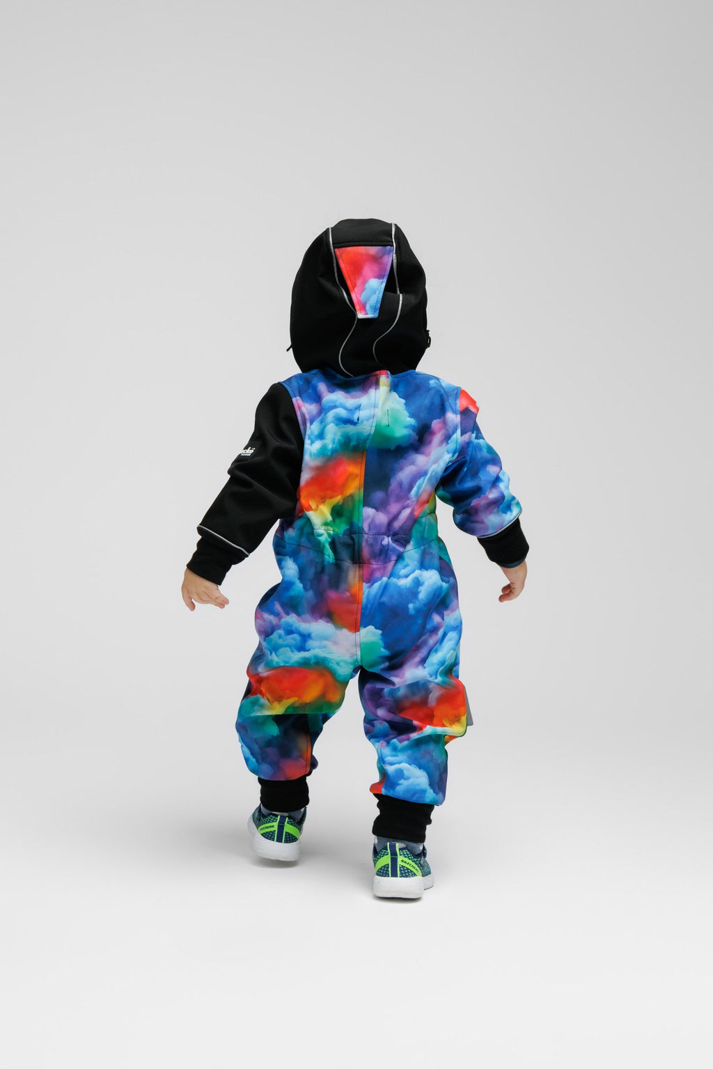 6. Back view of toddler in colorful softshell onesie with black hood, standing on white background