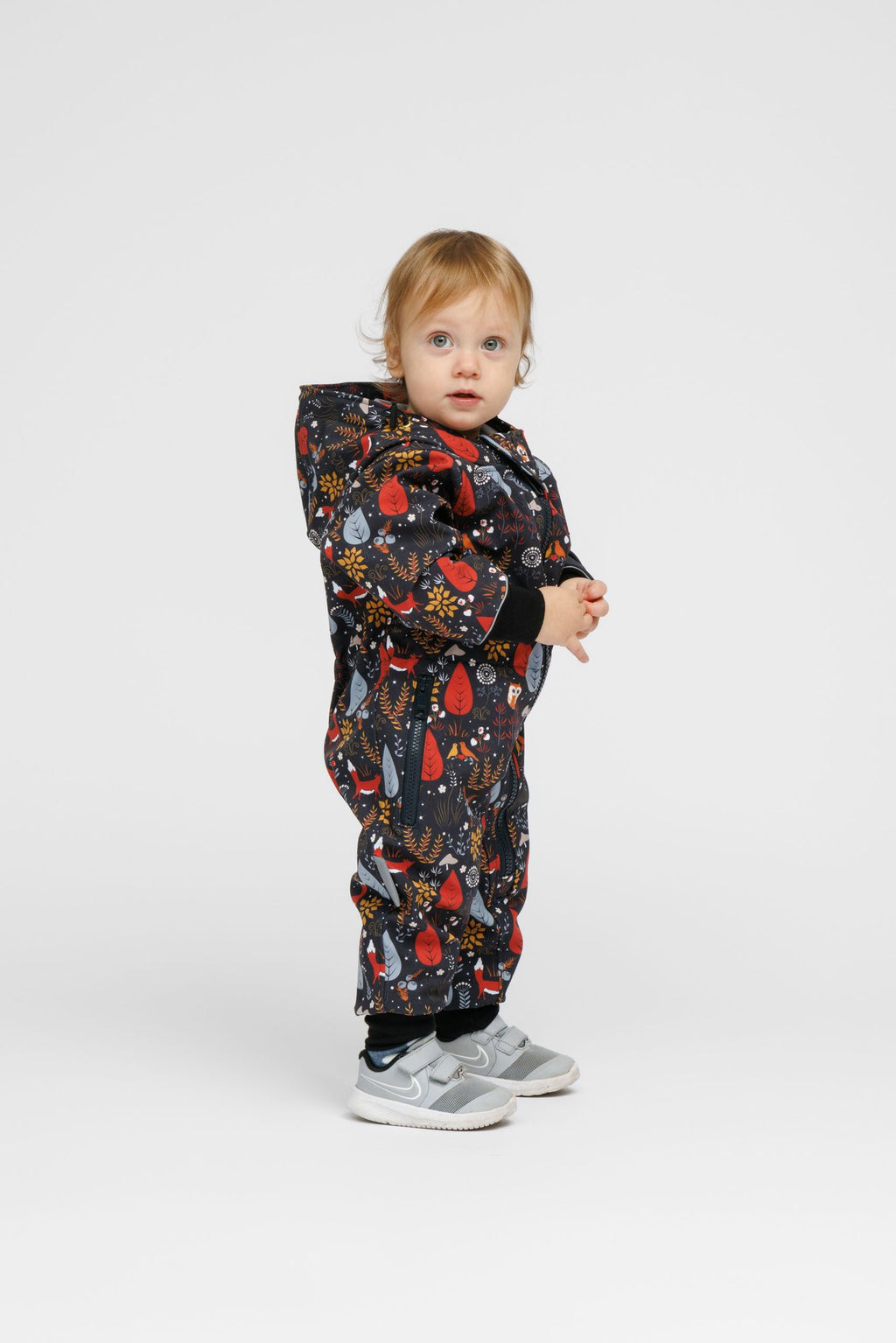 4. Toddler in Nuckö softshell onesie with forest print, standing sideways in studio