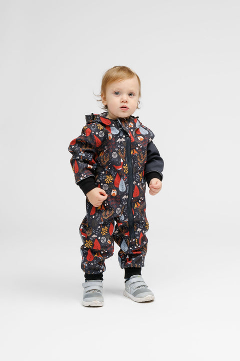 1. Toddler wearing Nuckö softshell onesie with forest print, standing in studio setting