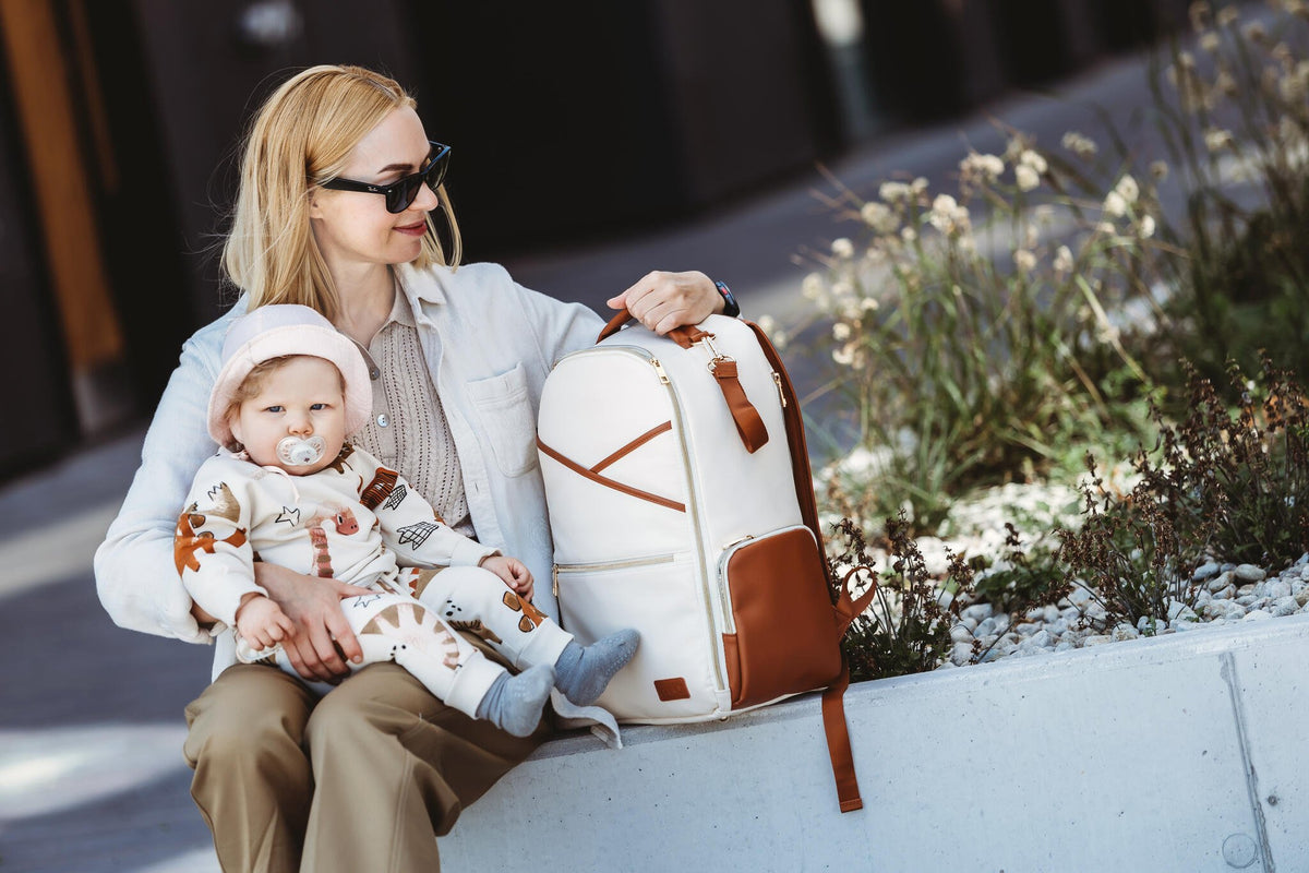 2. Woman holding baby with Ally Scandic Cappuccino Diaper Backpack, highlighting stylish design
