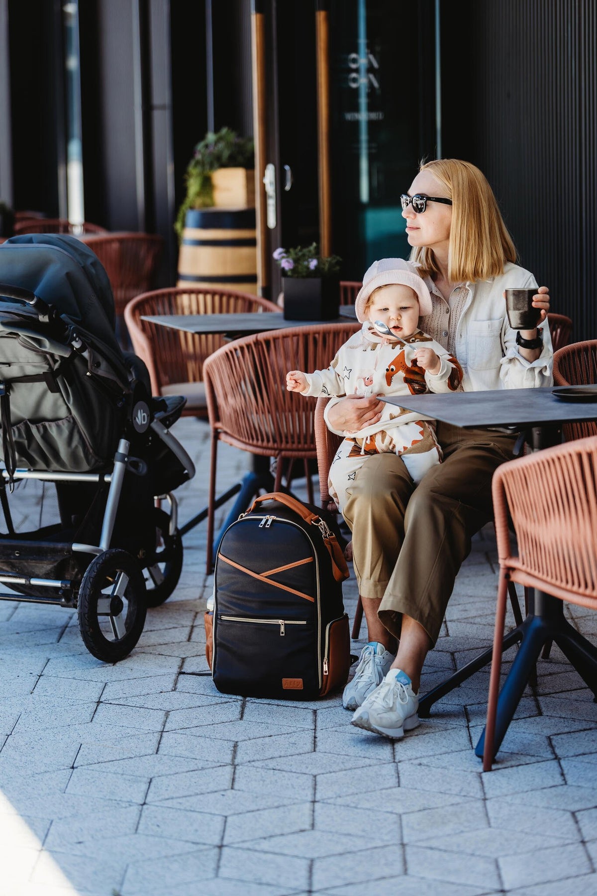 7. Woman with baby and Ally Scandic Black Coffee diaper backpack at outdoor cafe