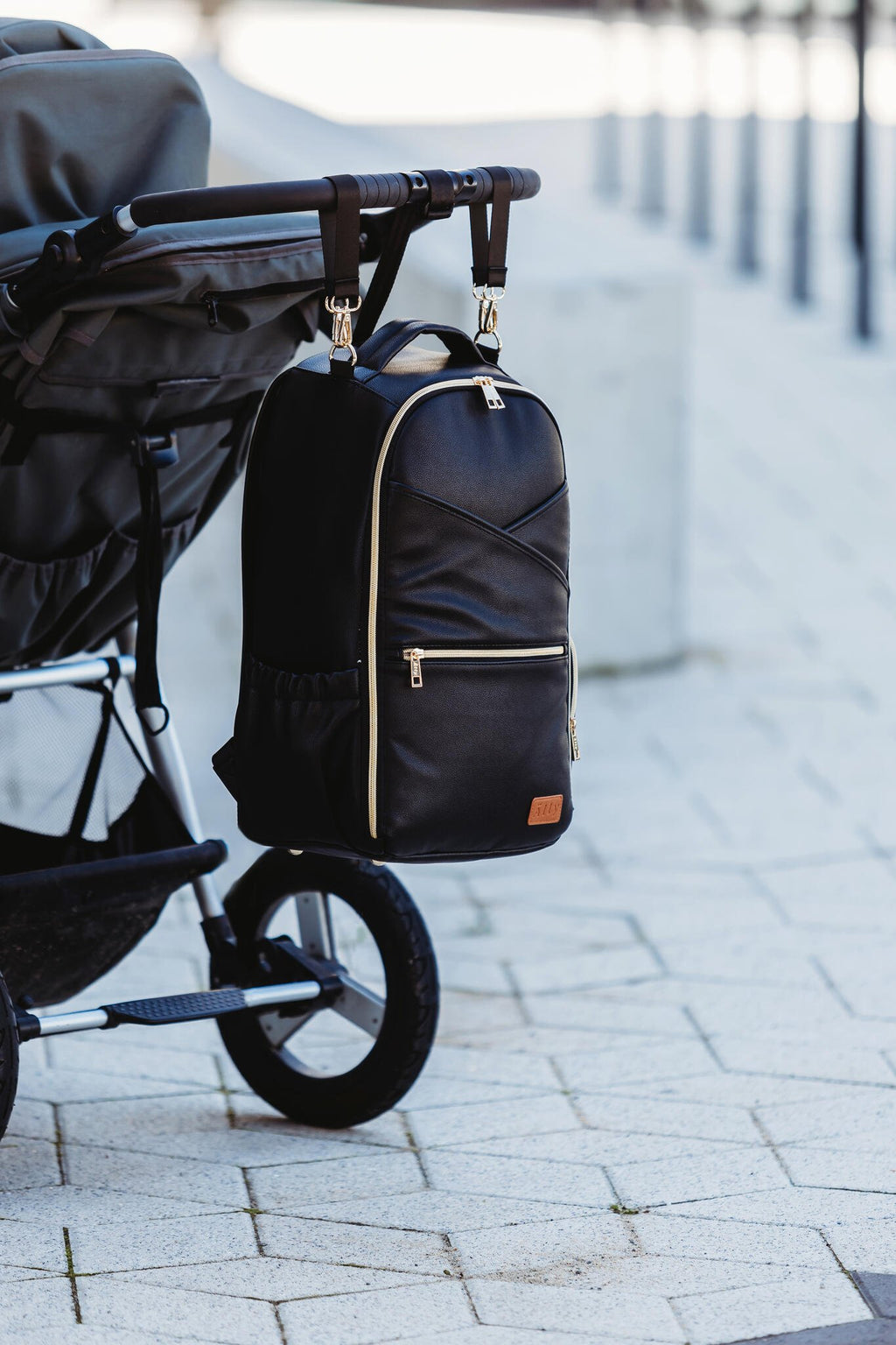 3. Ally Scandic Espresso Diaper Backpack attached to stroller, demonstrating stroller strap feature