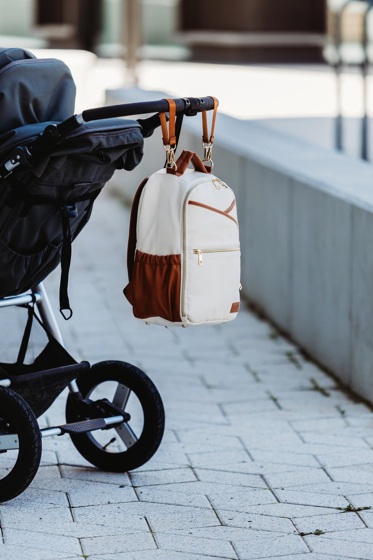 6. Ally Scandic small cappuccino diaper backpack attached to stroller in outdoor setting