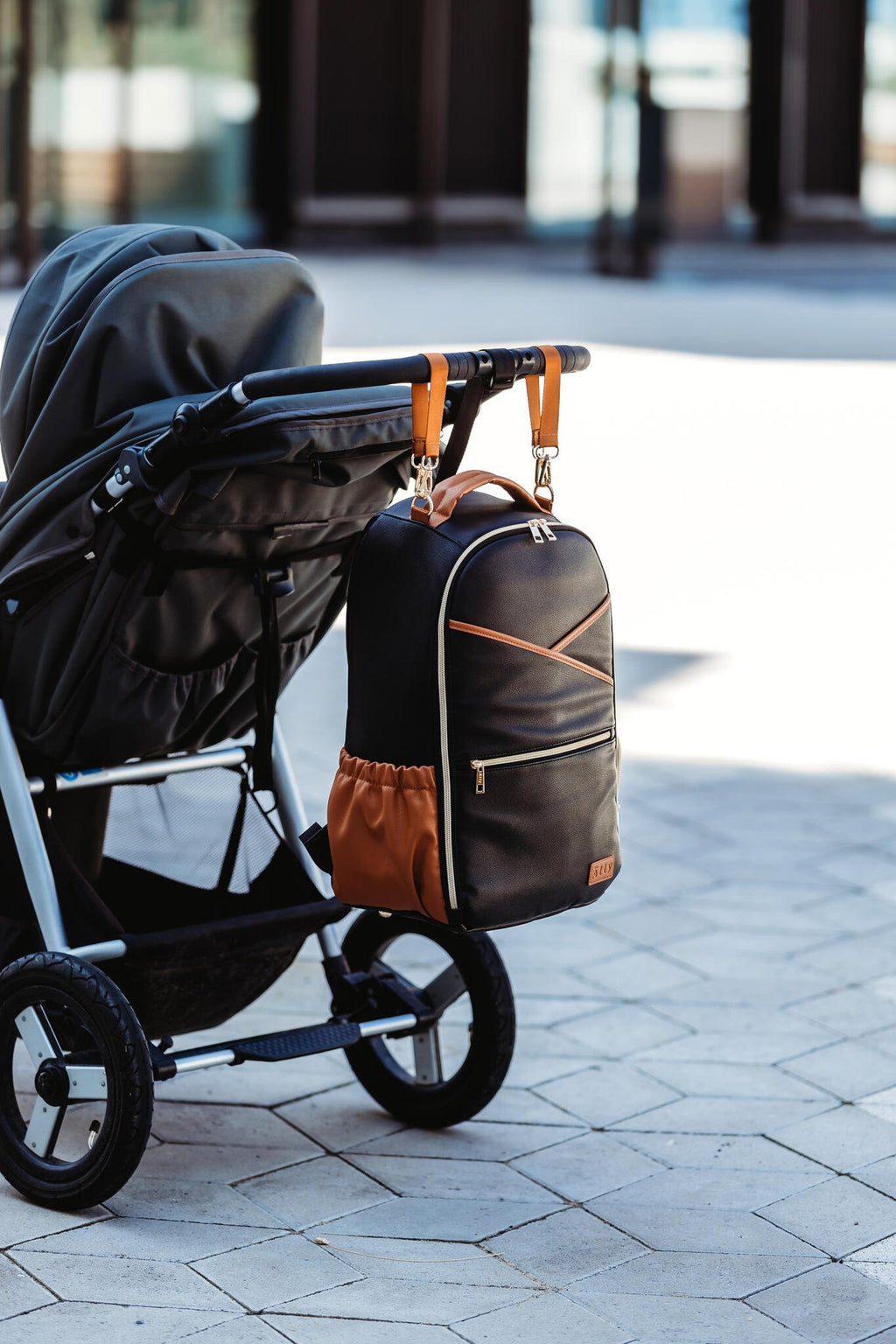 24. Ally Scandic Black Coffee diaper backpack attached to stroller in outdoor setting