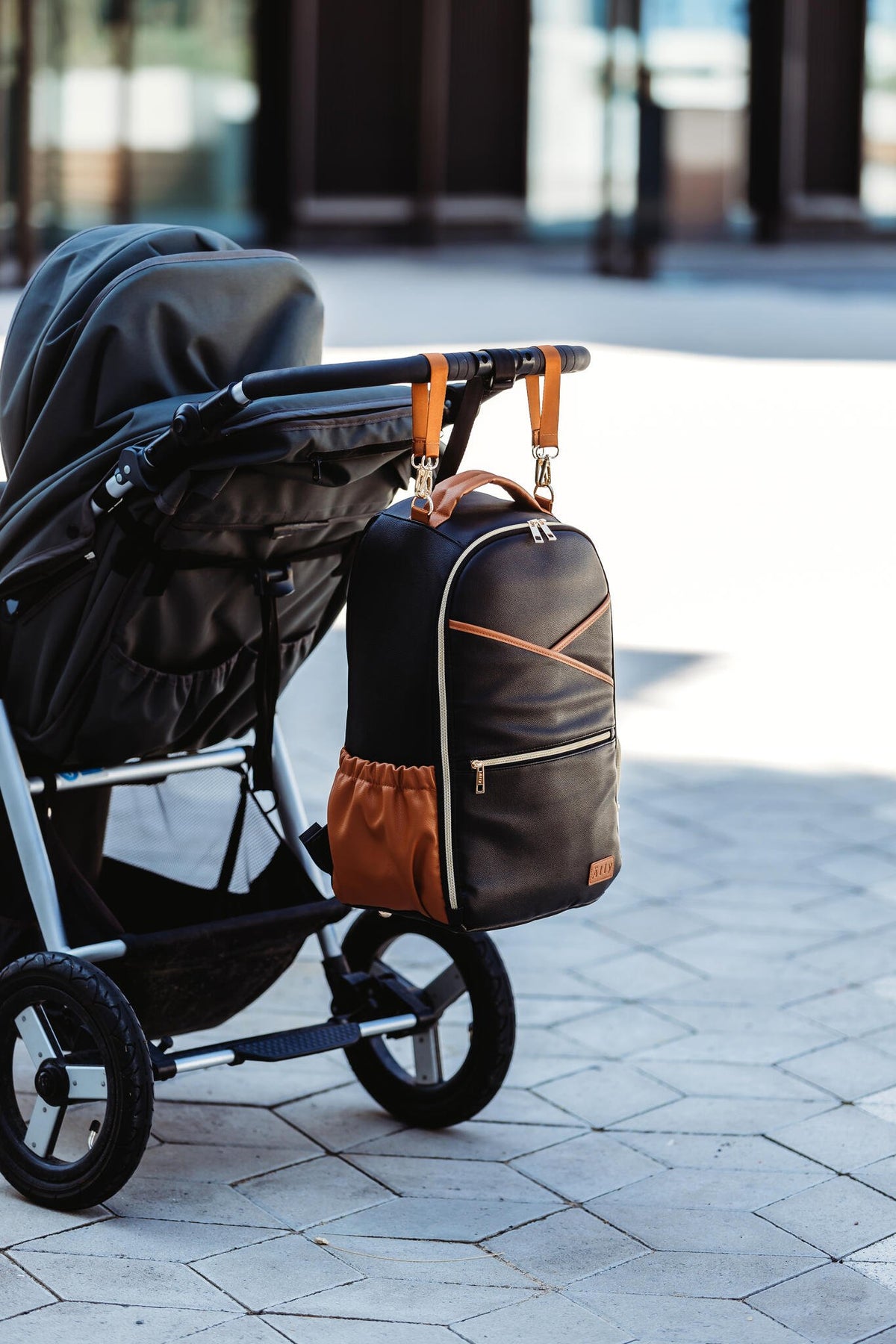 24. Ally Scandic Black Coffee diaper backpack attached to stroller in outdoor setting