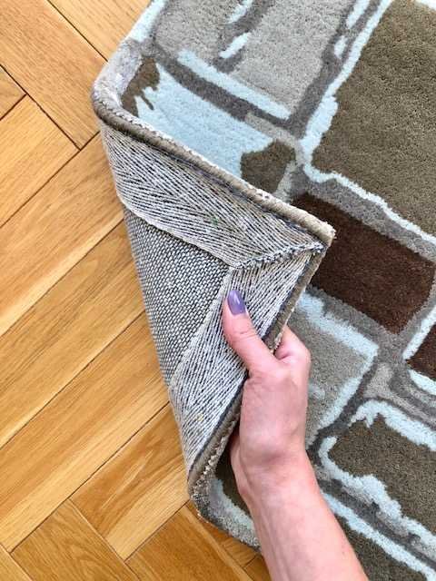 4. Detail of Mondrian in Earthy Hues rug with hand lifting corner to show backing and texture