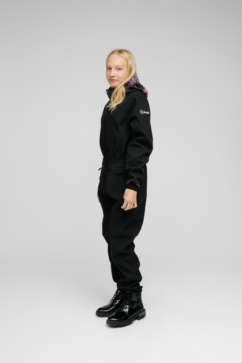 2. Side view of girl in Nuckö Pilv softshell onesie, showcasing adjustable waist and hood