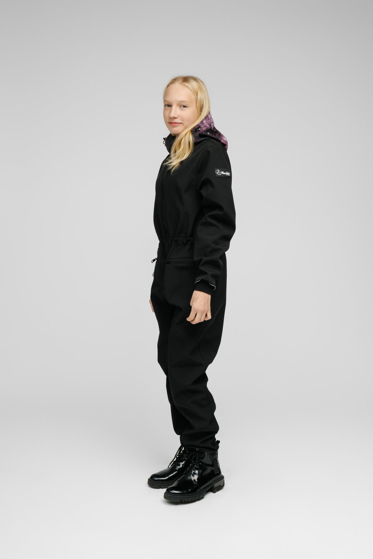2. Side view of girl in Nuckö Pilv softshell onesie, showcasing adjustable waist and hood