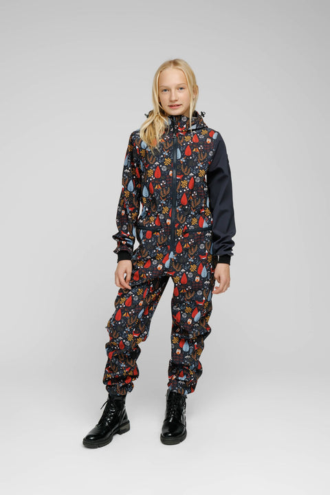 5. Child wearing Nuckö softshell onesie with forest print, standing in studio