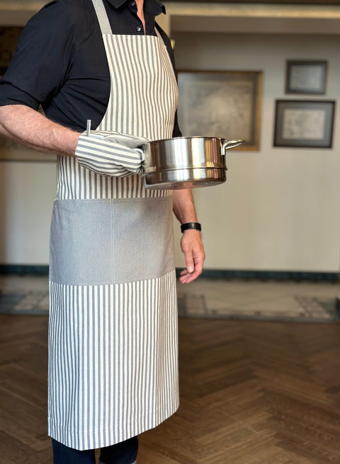 4. Unisex Nord 1 apron by Hortensias Home worn by male model holding pot, demonstrating functionality in kitchen