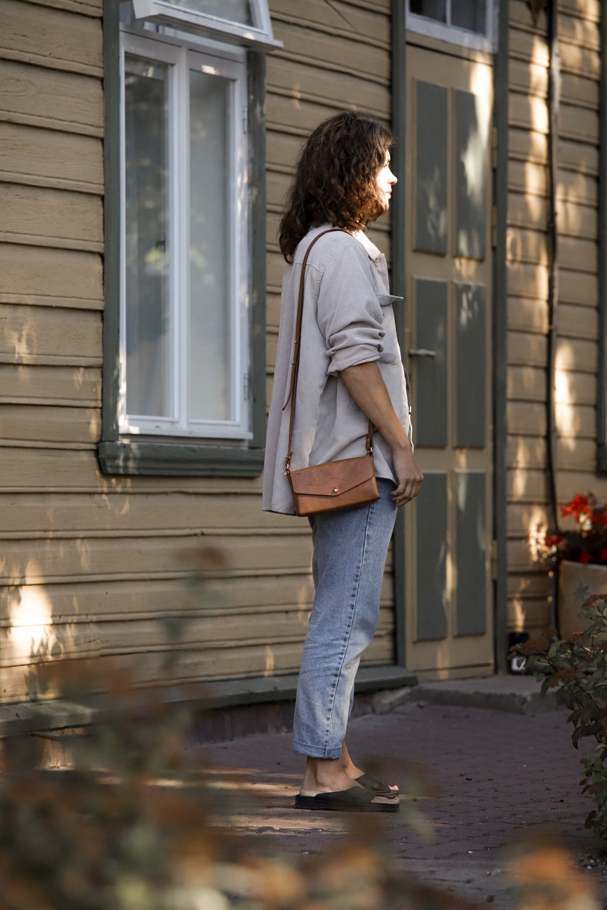 10. Woman wearing KOKUKA crossbody leather bag in tan, styled casually outdoors