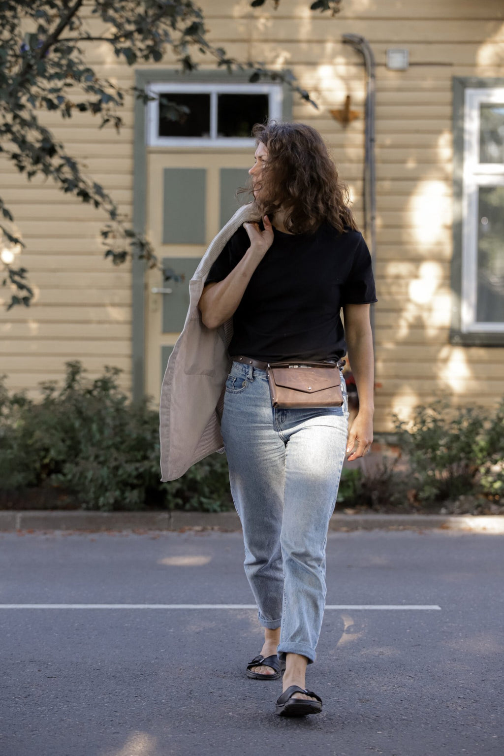 11. Woman wearing KOKUKA crossbody leather bag as a waist bag, styled with casual outfit outdoors