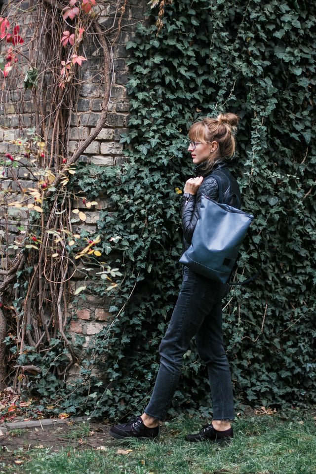 4. Muni faux leather grey backpack in natural setting with red branches