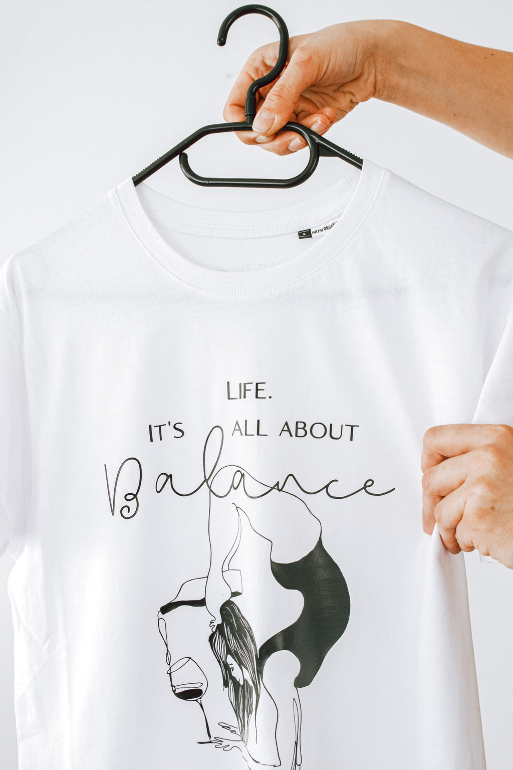 5. Detailed view of white 'It's All About Balance' T-shirt by Black Giraffe Brand, focusing on design and organic cotton material