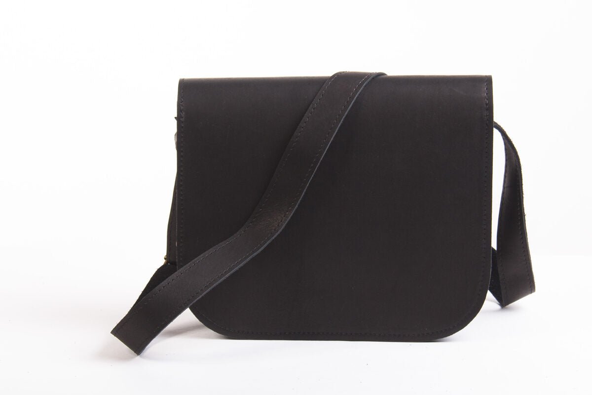 6. Back view of Zelma Kraft black leather saddle bag with adjustable strap in studio setting