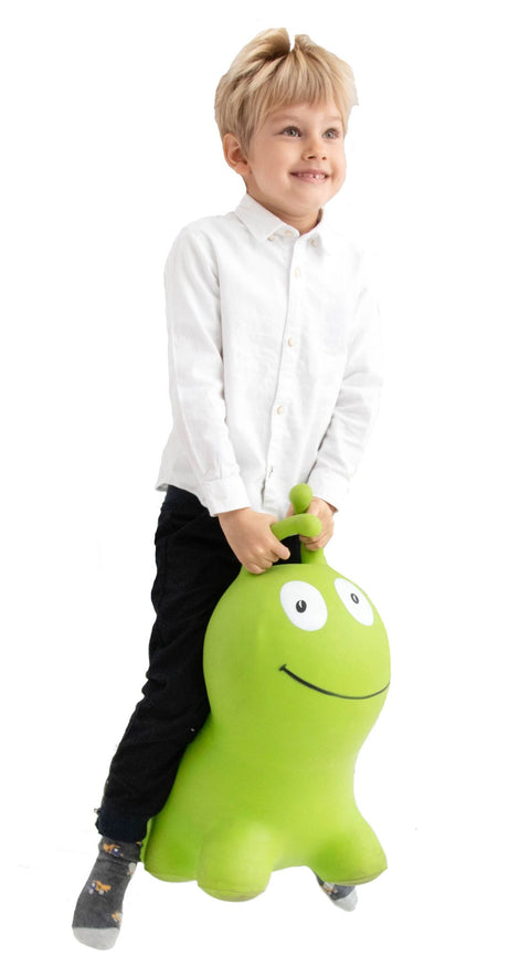1. Young boy wearing a white shirt and black pants riding a green worm-shaped hopper toy indoors