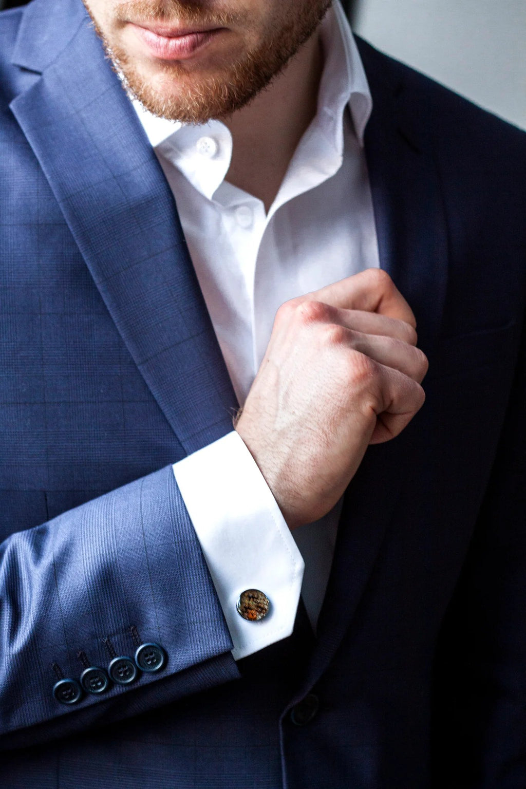 1. Man in blue suit wearing Eherüs red-spotted leather cufflinks adjusting his sleeve