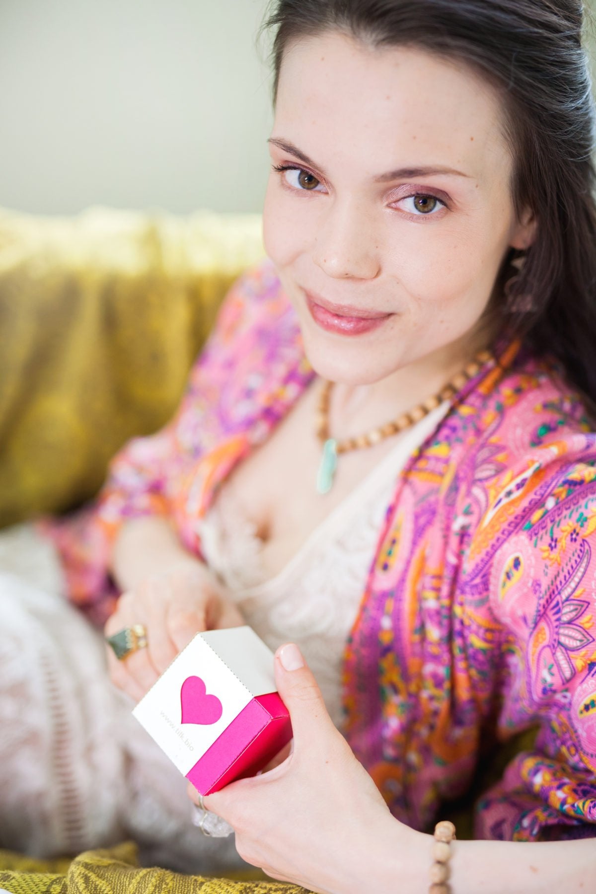 2. Woman holding Tilk! Love Me Moisturising Hand Cream box, smiling in a cozy environment