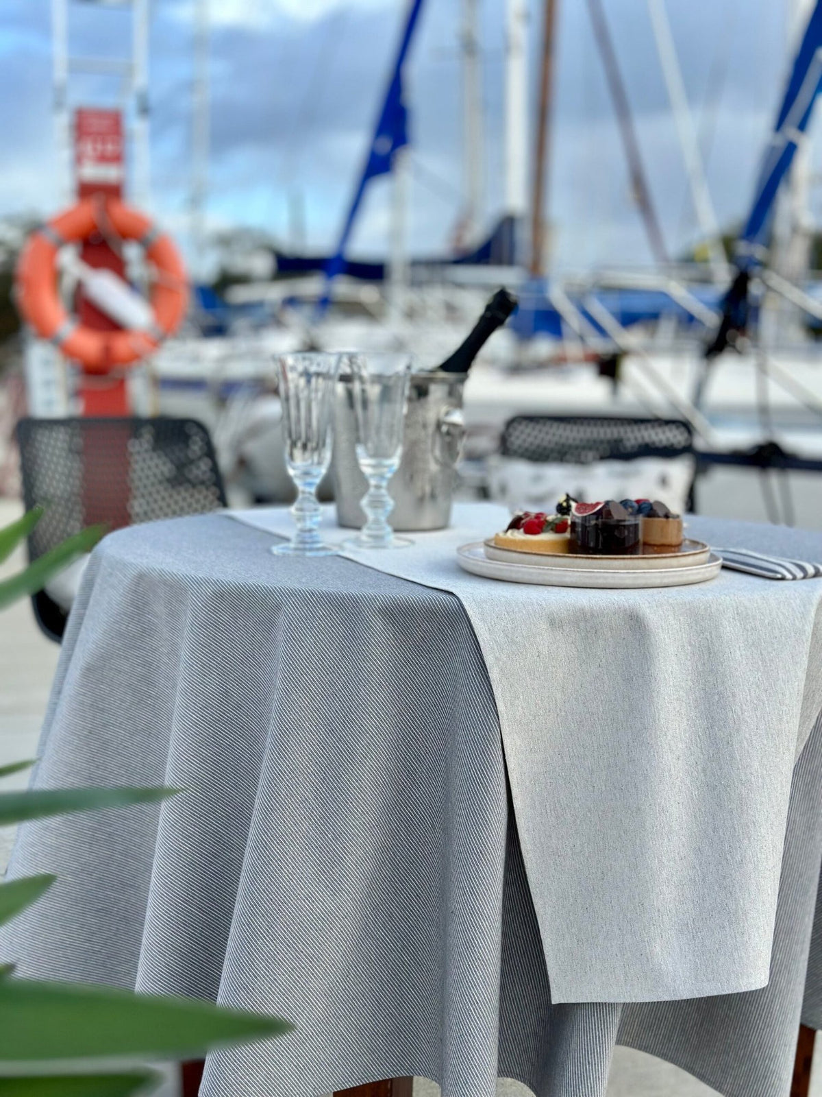 1. Hortensias Home Nord 3 table runner with blue stripes on outdoor dining table by marina, showcasing eco-friendly design