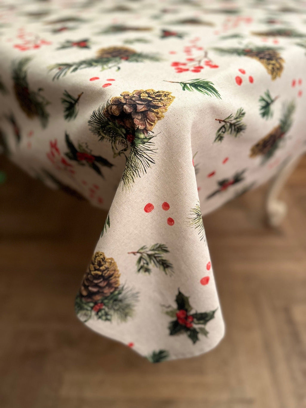 3. Studio shot of Winter Motive Golden Pine tablecloth draped over table, highlighting festive design and cotton-polyester blend