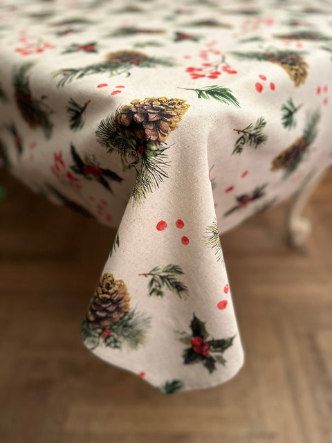 3. Studio shot of Winter Motive Golden Pine tablecloth draped over table, highlighting festive design and cotton-polyester blend