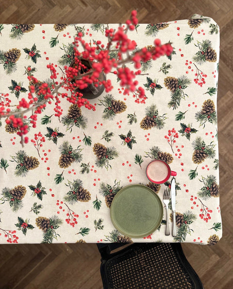 1. Lifestyle image of Winter Motive Golden Pine tablecloth by Hortensias Home, featuring festive pine and berry design on dining table