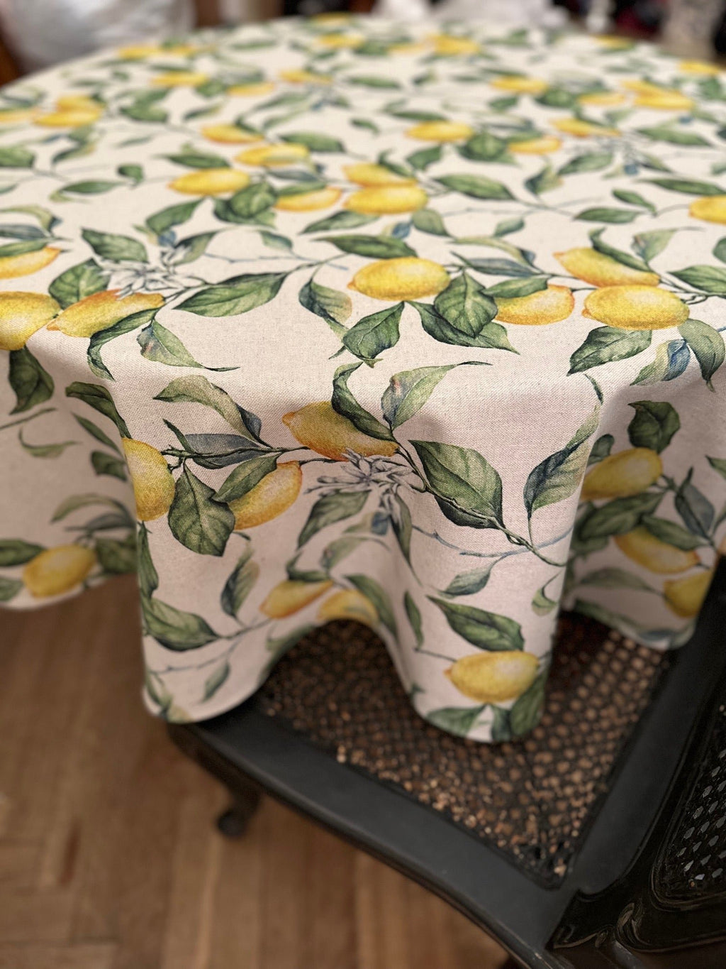 2. Side view of Hortensias Home Lemon Linen round tablecloth showcasing lemon and leaf pattern, draped over a dining table