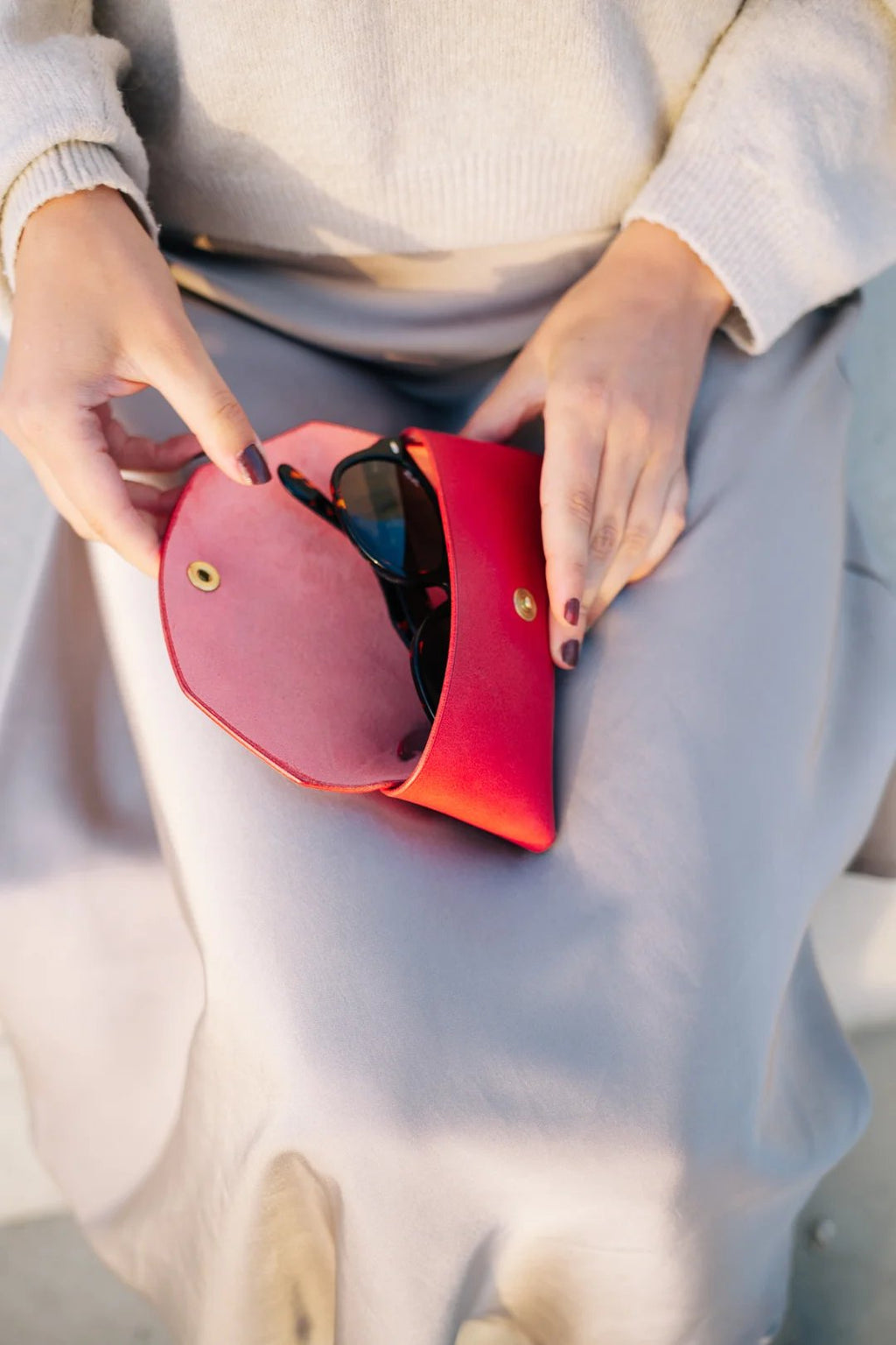 3. Close-up of Mirgoods red leather sunglasses case with sunglasses inside