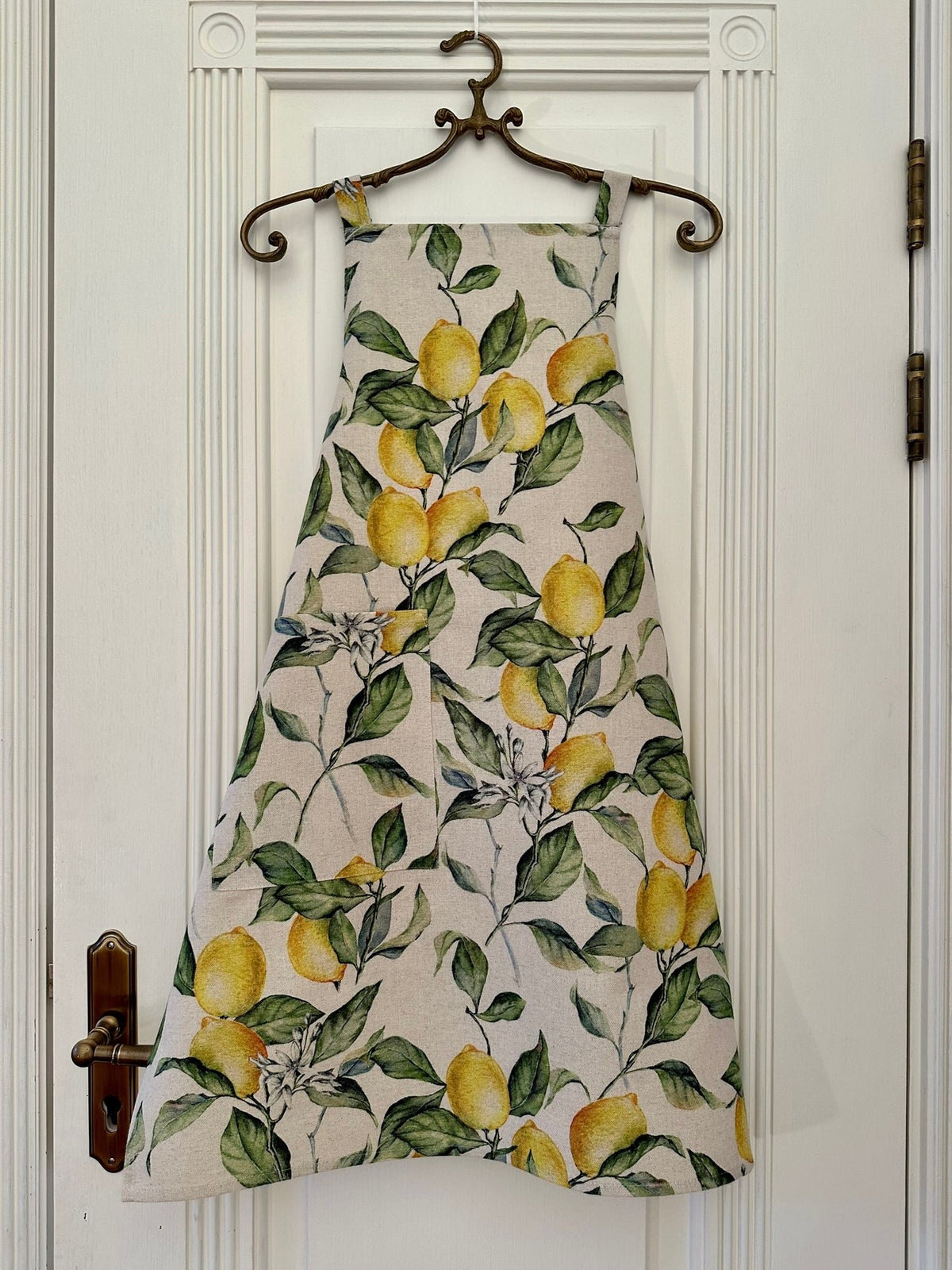 1. Ladies' apron in lemon linen with vibrant lemon print, hanging on a door, showcasing European craftsmanship by Hortensias Home