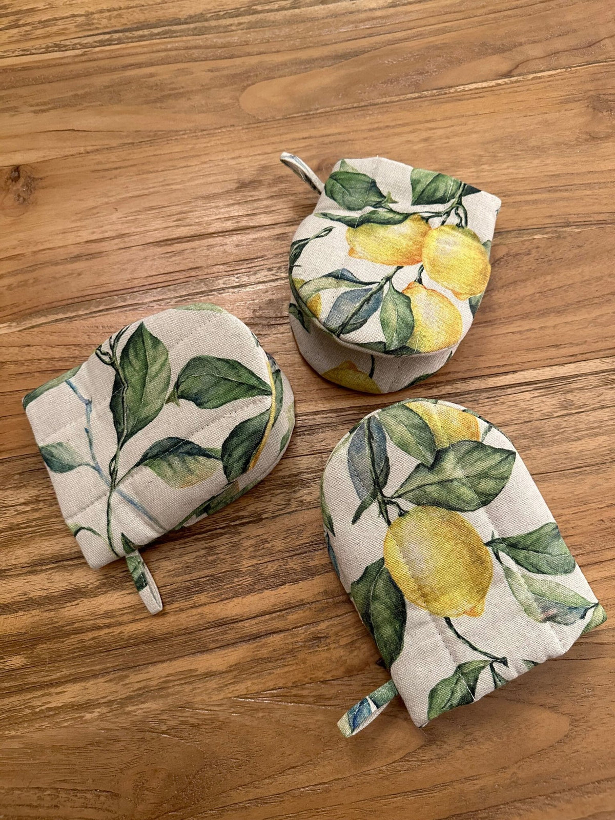 3. Flat lay of Hortensias Home Lemon Linen oven gloves with lemon motif, displayed on wooden surface