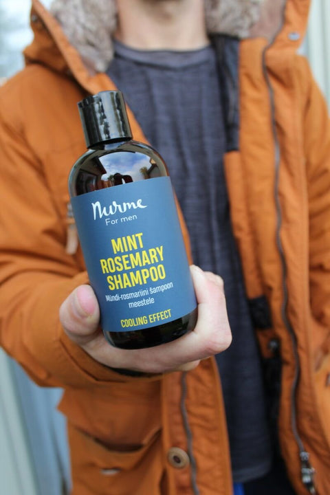 5. Man holding Nurme mint rosemary shampoo, showcasing product in lifestyle setting