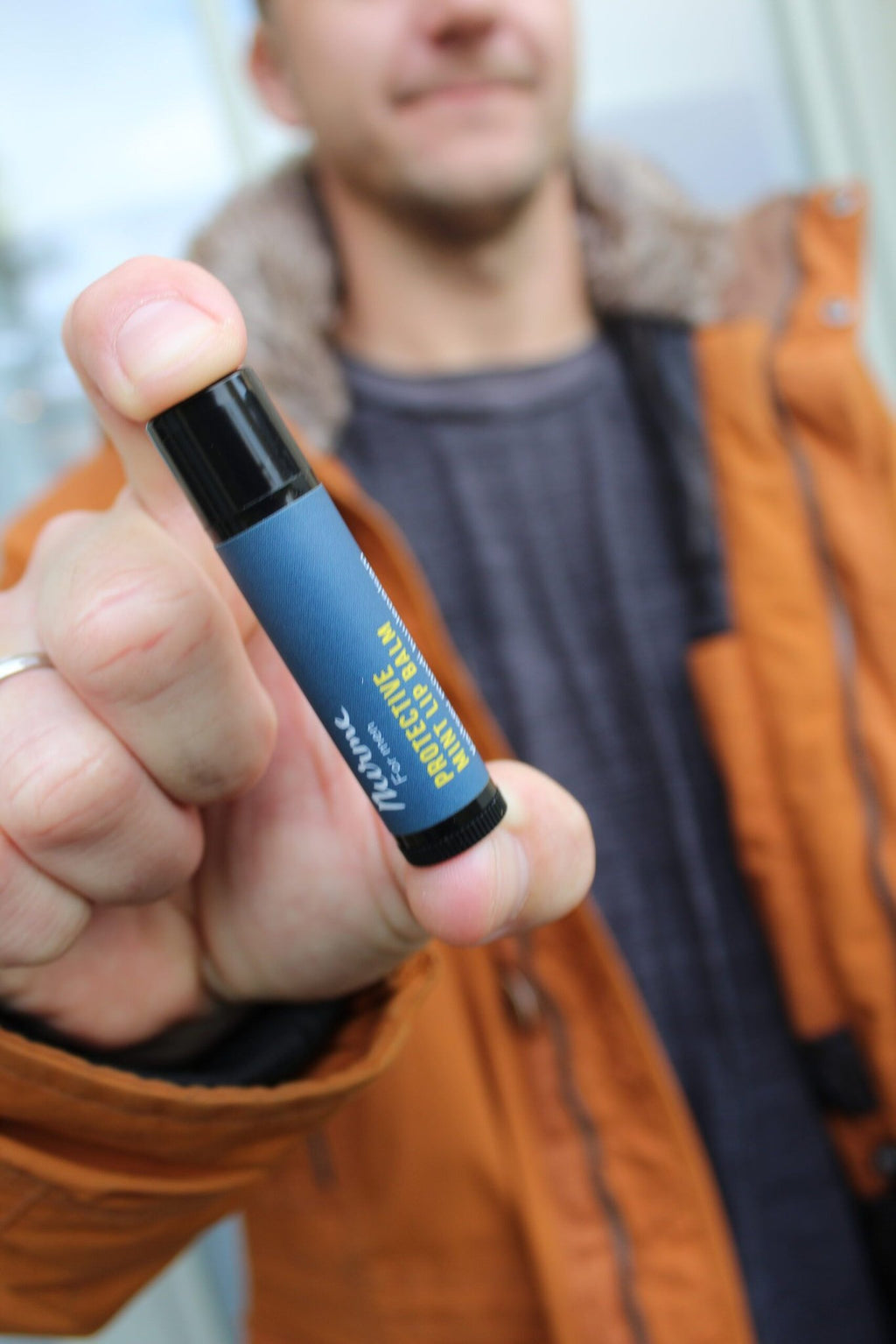 6. Man holding Nurme Protective Mint Lip Balm, highlighting product in lifestyle context