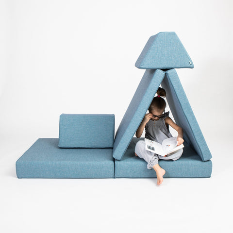 1. Child reading inside a turquoise play tent made from Monboxy activity play mattress set in a studio setting