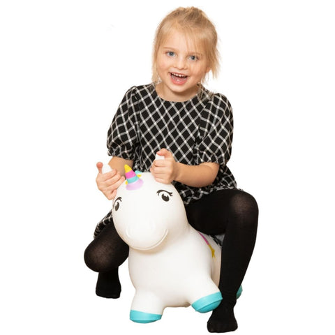 1. Smiling girl in black dress riding white unicorn hopper with colorful mane, in studio setting