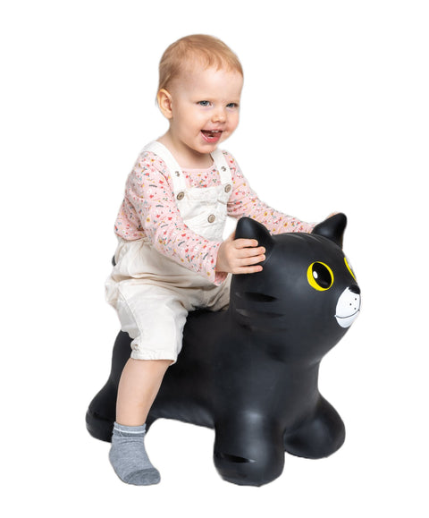 1. Child wearing white overalls sitting on black cat-shaped hopper toy with yellow eyes on black background