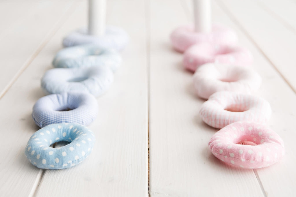 3. Close-up of blue and pink Karloova stacking rings lined up on white wooden floor