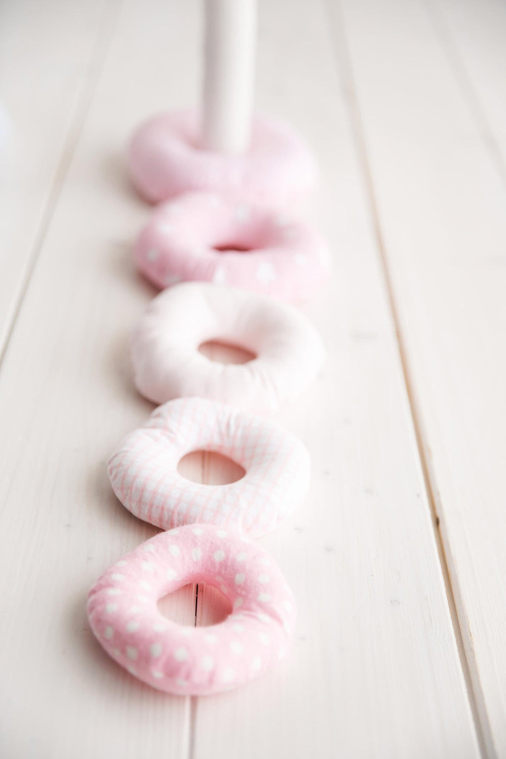 3. Close-up of pink Karloova stacking rings lined up on white wooden floor