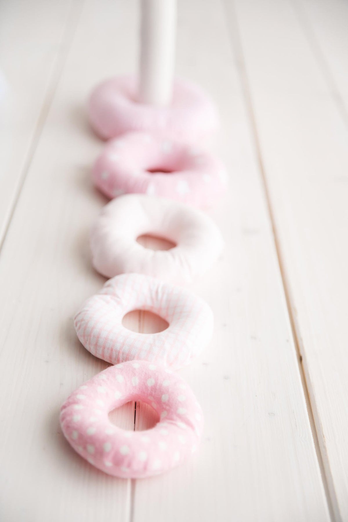 3. Close-up of pink Karloova stacking rings lined up on white wooden floor