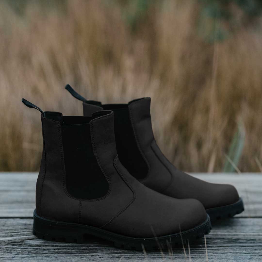 2. Pair of KIRA 3.0 Chelsea Boots in black on wooden surface with natural background