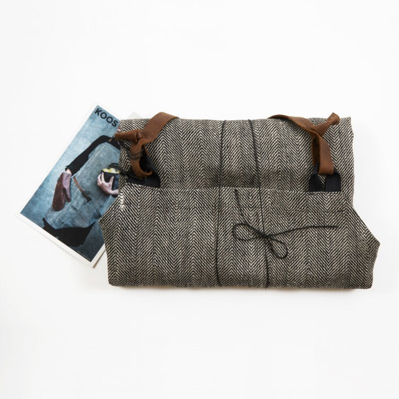 4. Flat lay of folded KOOSdisain herringbone linen apron with leather straps, accompanied by a product card on a white background