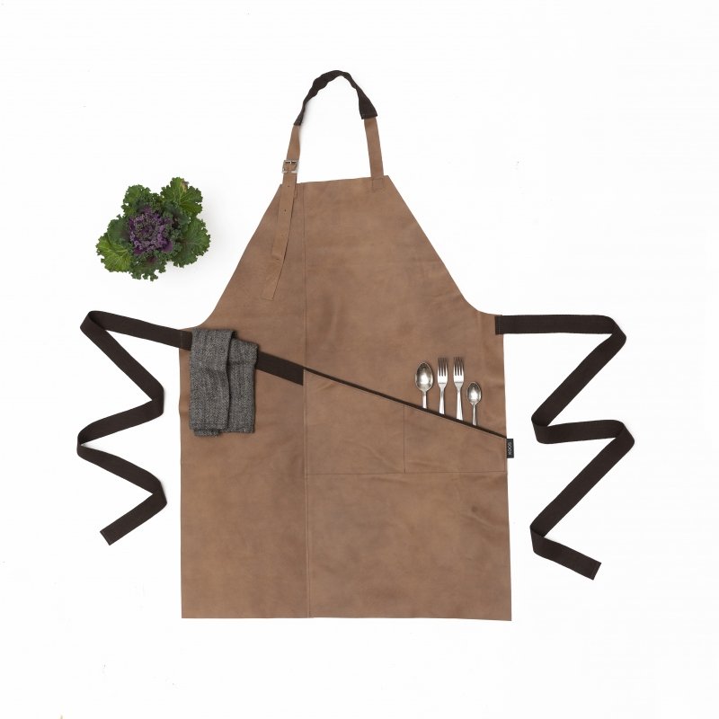 4. Flat lay of beige leather apron with brown belt, pocket holding cutlery, and towel, next to green plant